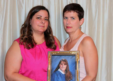 Surviving sisters Lisa and Rani, with a photo of their youngest sister, who was murdered